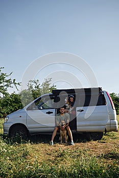 Concept of digital nomad with Caucasian people on romantic journey in minivan. Couple with dogs traveling together on