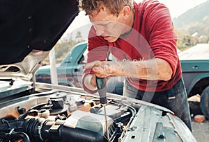 The concept of disability of people and their adaptation to life. A blond disabled man repairs a car, works with a screwdriver.