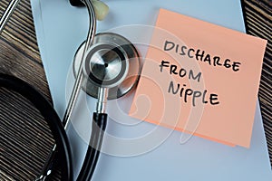 Concept of Discharge From Nipple write on sticky notes with stethoscope isolated on Wooden Table