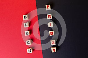 Concept of discounts and sales. On a red and black background are wooden cubes with the inscription black Friday. Flat lay.