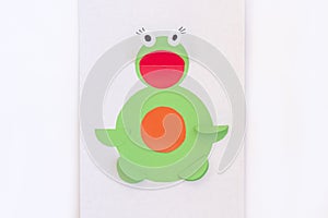 Concept of DIY and children`s creativity. Step by step instruction: how to make applique frog from paper. Step 6 finished result