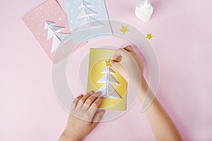 Concept of DIY and kid`s creativity, origami. Step by step instruction: how to make greeting cards with christmas trees origami.