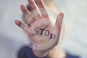 Concept of domestic violence and child abusement. A little girl shows her hand with the word STOP written on it. Children violence