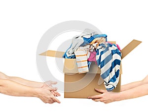 The concept of donating. Hands are giving a box of clothes to other hands