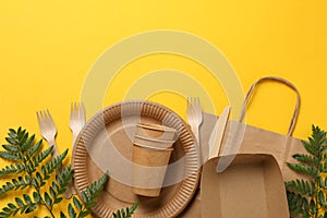 Concept with eco - friendly tableware and plant on yellow background