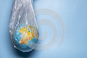 The concept of ecology. Globe in plastic wrap on a blue background. plastic waste environmental pollution concept