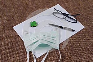 The concept of ecology, nature protection. Background - clean paper, leaf of green clover and a protective mask. photo