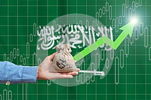 The concept of economic growth in Kingdom of Saudi Arabia. Hand holds a bag with money and an upward arrow