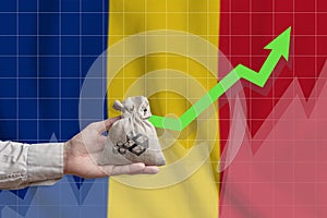 The concept of economic growth in Romania. Hand holds a bag with money and an upward arrow