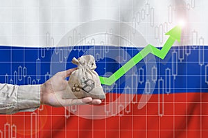 The concept of economic growth in Russian Federation. Hand holds a bag with money and an upward arrow