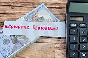 Concept of Economic Slowdown write on sticky notes with dollars isolated on Wooden Table