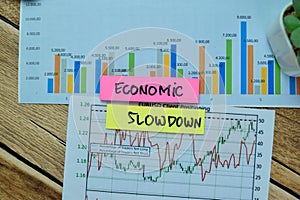 Concept of Economic Slowdown write on sticky notes with stock market isolated on Wooden Table photo