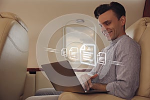 Concept of electronic signature. Man using laptop in airplane during flight