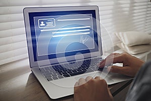 Concept of electronic signature. Man working on laptop at wooden table indoors, closeup