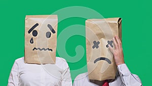 Concept of emotions, gestures. a couple of people with bags on their heads, with a painted emoticon, sad, crying, tired
