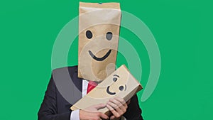 Concept of emotions, gestures. man with a package on his head, with a painted emoticon, smile, joy, laughter. plays with