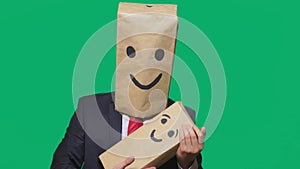 Concept of emotions, gestures. man with a package on his head, with a painted emoticon, smile, joy, laughter. plays with