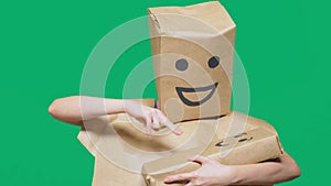 Concept of emotions, gestures. man with a package on his head, with a painted emoticon, smile, joy, laughter. plays with