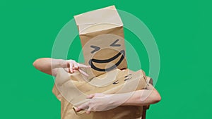 Concept of emotions, gestures. man with a package on his head, with a painted emoticon, smile, joy, laughter. plays with