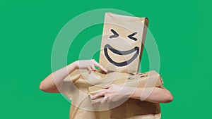 Concept of emotions, gestures. man with a package on his head, with a painted emoticon, smile, joy, laughter. plays with