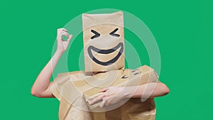 Concept of emotions, gestures. man with a package on his head, with a painted emoticon, smile, joy, laughter. plays with