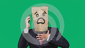 Concept of emotions, gestures. a man with paper bags on his head, with a painted emoticon, fear. talking on a cell phone