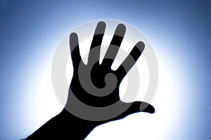 Silhouette of five fingers on a man`s hand with a bright light spot. The concept of entreaty for help or greetings. Blue photo