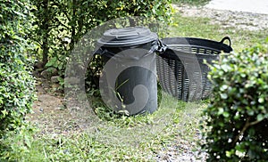 Concept of environment preservation, black plastic recycle bins placed in the garden for cleanness