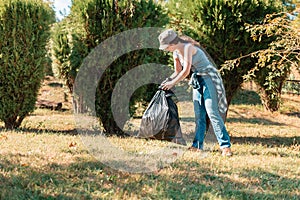 The concept of environmental pollution and Earth day. A female volunteer cleans the Park, collecting garbage bags in one place