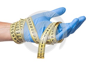 Concept of excess weight, weight loss, liposuction. Doctor in blue glove and measuring tape in his hands is isolated on white