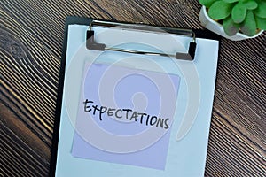 Concept of Expectations write on sticky notes isolated on Wooden Table