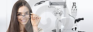 Concept of eye examination, woman patient smiling with spectacles  in optician office with diagnostic tools in white