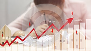 Concept of falling real estate market, down arrow and wooden house. The concept of falling property prices. Lower housing prices.