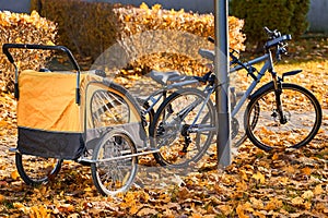 The concept of a family tourist holiday with a child. Yellow bicycle stroller for children on the background of foliage