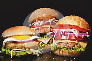 Concept: fast food big burgers on a black table. Large double cheeseburger with cutlets and fresh vegetables on a dark background.