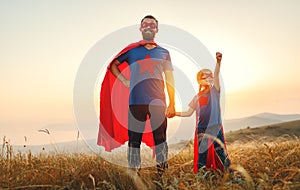 Concept of father`s day. dad and child daughter in hero superhero costume at sunset