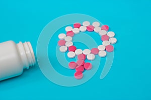 Concept Female health, female contraception. Gender symbol made from pink and white pills or tablets with the bottle on