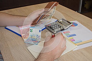 The concept of financial planning, savings. Man, Money with calculator and notebook on wood table. Photo shows a closeup of busine