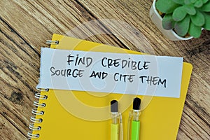 Concept of Find Credible Source and Cite Them write on sticky notes isolated on Wooden Table photo