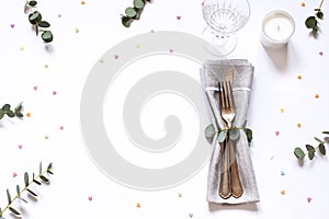 Concept flat lay with floral decorations and cutlery on the white backdround.