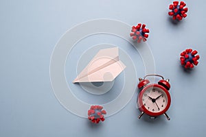 Concept of fly danger. Paper plane and models of covid-19 virus on blue background