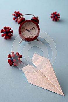 Concept of fly danger. Paper plane and models of covid-19 virus on blue background