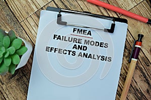 Concept of FMEA - Failure Modes and Effects Analysis write on paperwork isolated on Wooden Table