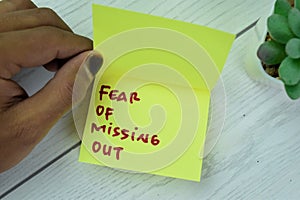 Concept of FOMO - Fear Of Missing Out write on sticky notes  on Wooden Table