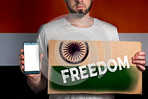 Concept of freedoms and human rights. A man with a cardboard and a phone in his hand. The Flag of India. Text freedom