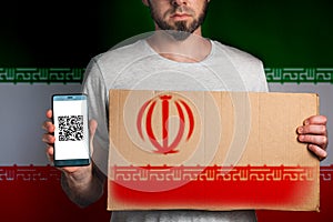 Concept of freedoms and human rights. A man with a cardboard and a phone in his hand. The Flag of Iran. Copy space