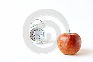 The concept of frequent fruit snacks during the working day. Red apple close-up on the clock background, light background, space