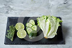 Concept of fresh green lettuce, cucumber, dill, lime on a light background, selective focus, top view, copy space.