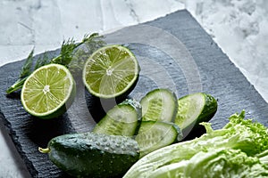 Concept of fresh green lettuce, cucumber, dill, lime on a light background, selective focus, top view, copy space.