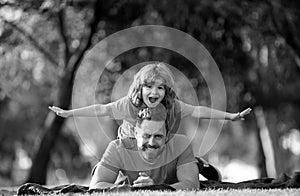 Concept of friendly family. Father and son laying on grass in summer park spending time outdoor together.